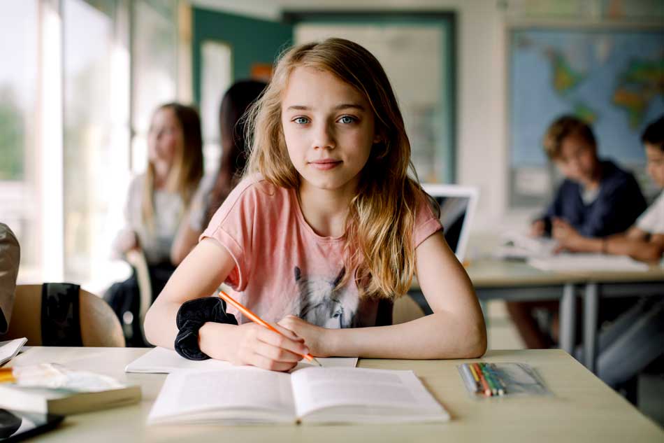 Flicka som sitter vid skolbänken