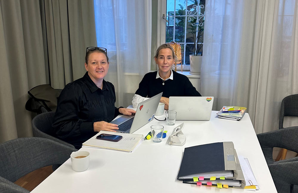 Två kollegor sitter vid ett bord med laptops