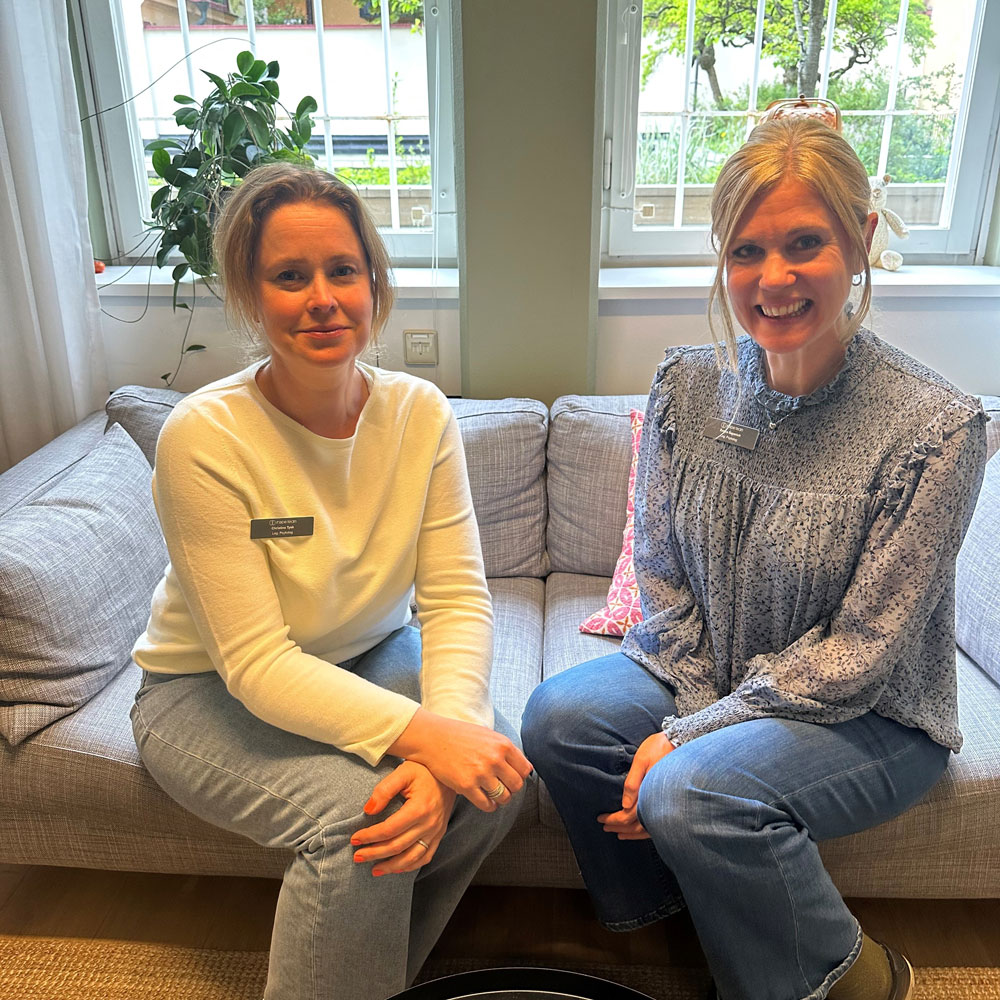 Två kollegor sitter i soffan och ler