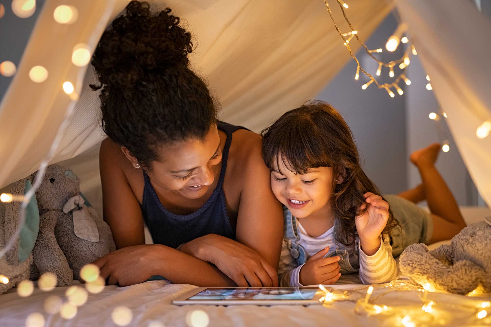 Mamma och dotter som ligger i en koja och läser